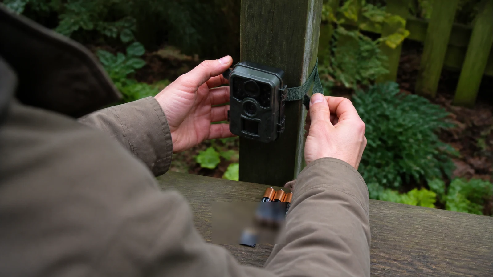 Beginner checking a trail camera mount and spare batteries in a UK garden